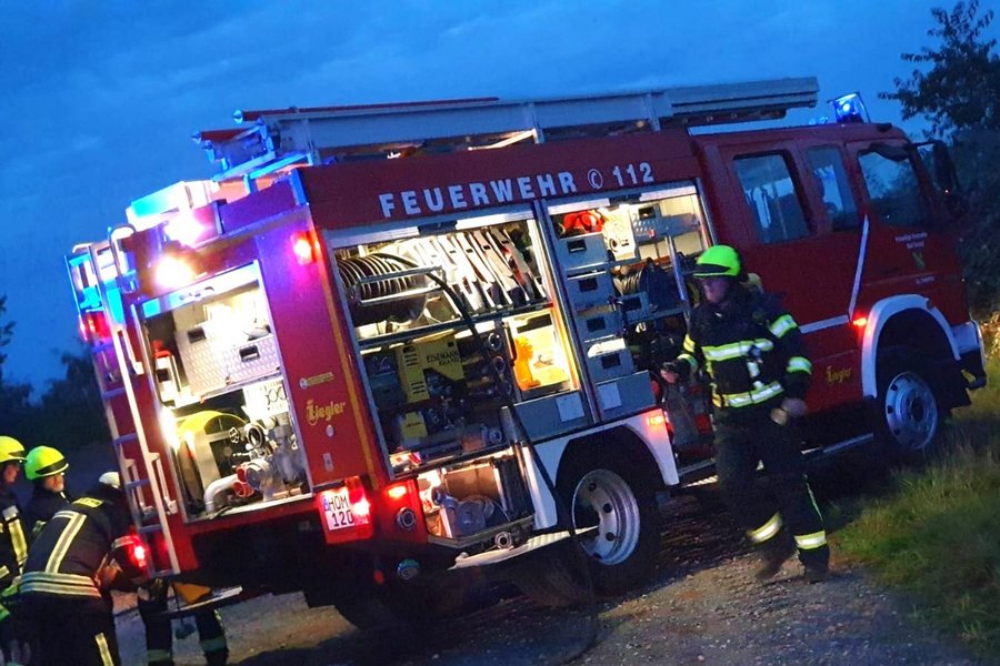 Feuerwehrmänner entnehmen Material aus Feuerwehrauto